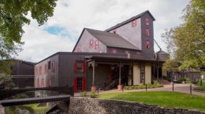 Maker's Mark Distillery in Kentucky, showcasing its distinctive black and red buildings and charming walkways, surrounded by greenery.